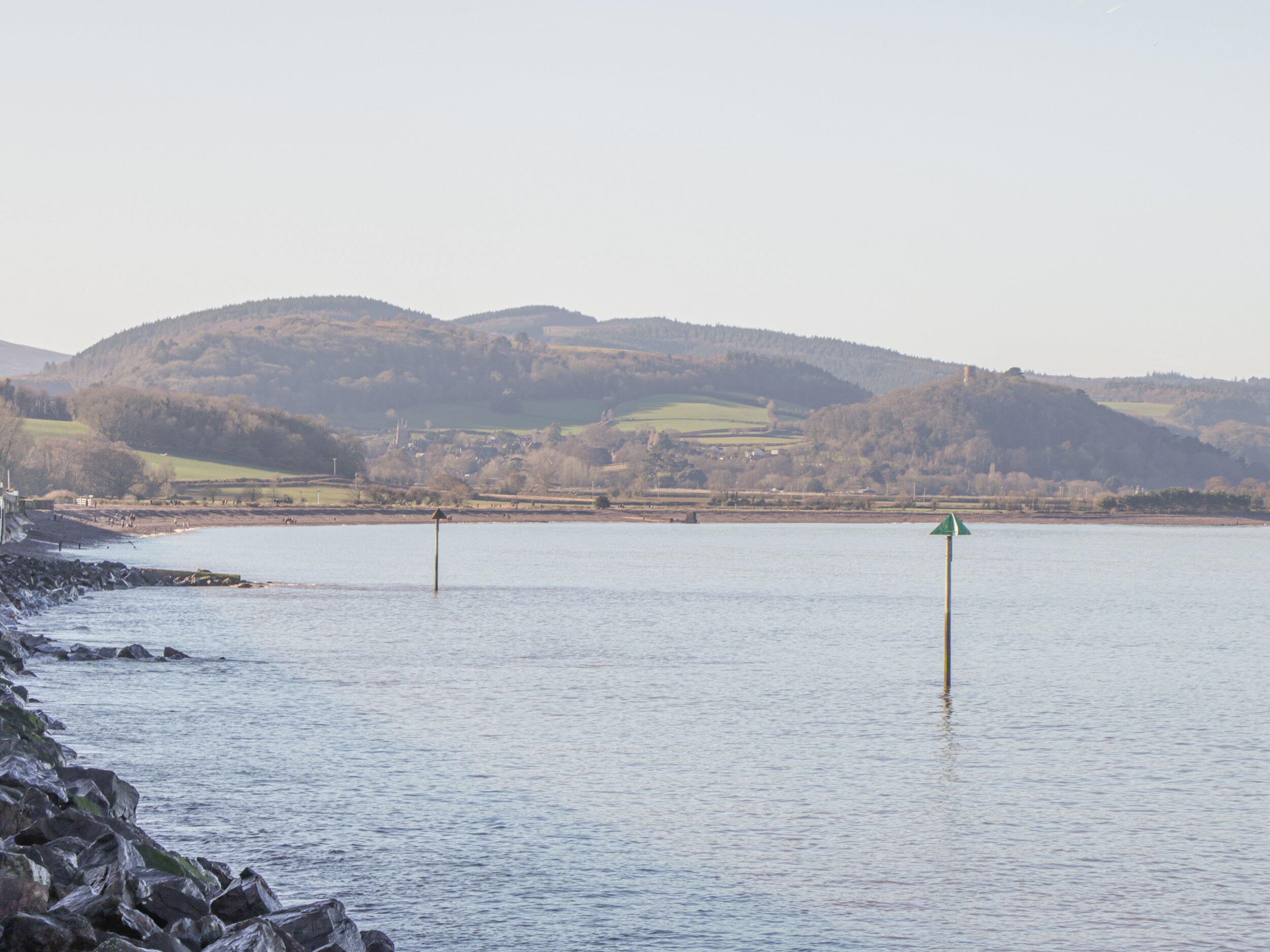 A calm lake with rocky shores and distant hills.
