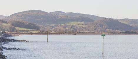 A calm lake with rocky shores and distant hills.