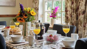 A breakfast table set with bowls, glasses, a coffee pot, and a fruit bowl. - Manor Cottage (Northallerton)