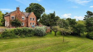 A large brick house with multiple windows, surrounded by a well-maintained lawn and various trees. - Manor Cottage (Northallerton)