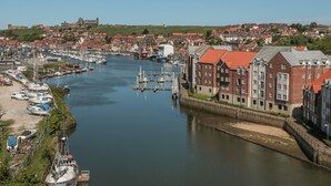 A harbor with boats, a bridge, and red-roofed buildings.