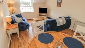 A cozy living room with a blue sofa, a wooden coffee table, and a TV stand.