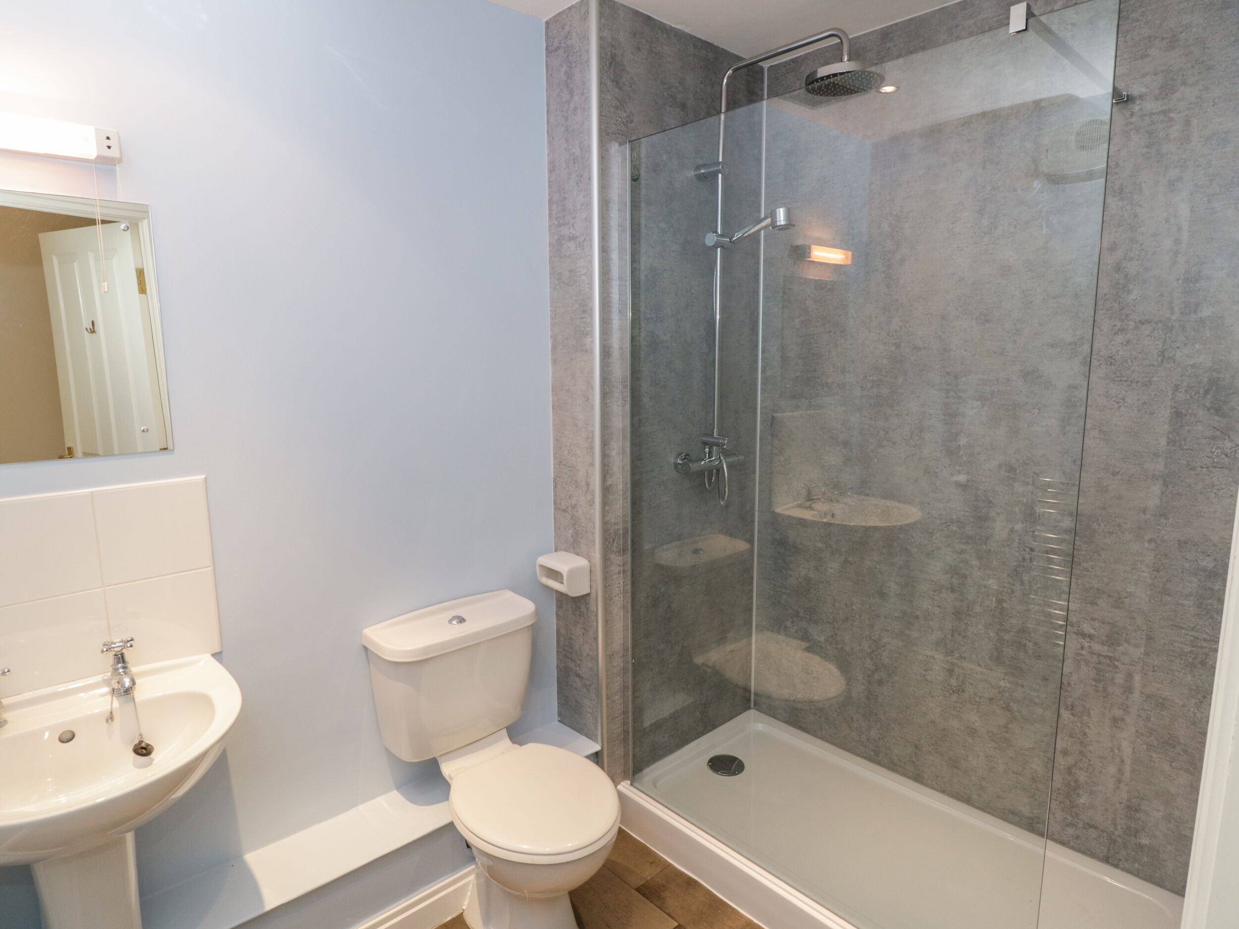 Un bagno con doccia vetrata, un WC bianco e un lavandino.