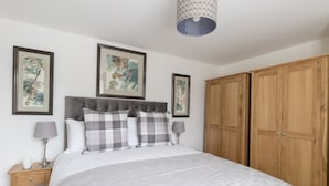 Une chambre à coucher avec un grand lit, une armoire en bois et deux œuvres d’art encadrées accrochées au mur.