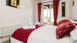 A hotel room with a bed, red curtains, a white door, and a window with a view of the outside. - Valley Lodge 52 (Gunnislake)