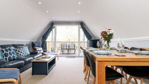 A modern loft-style living space with a dining area, a sofa set, and a view of the outdoors. - Valley Lodge 52 (Gunnislake)