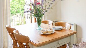 Une table à manger avec des chaises, un vase rempli de fleurs et des assiettes avec des petits gâteaux.