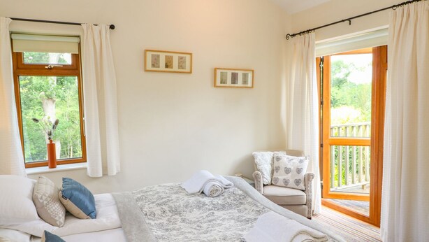 Une chambre à coucher avec un lit, une chaise, une fenêtre et un balcon.