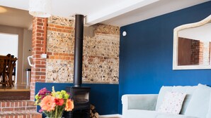 Ein Wohnzimmer mit Kamin aus Backsteinen, einem weißen Sofa und einem Blumenstrauß auf einem Tisch.