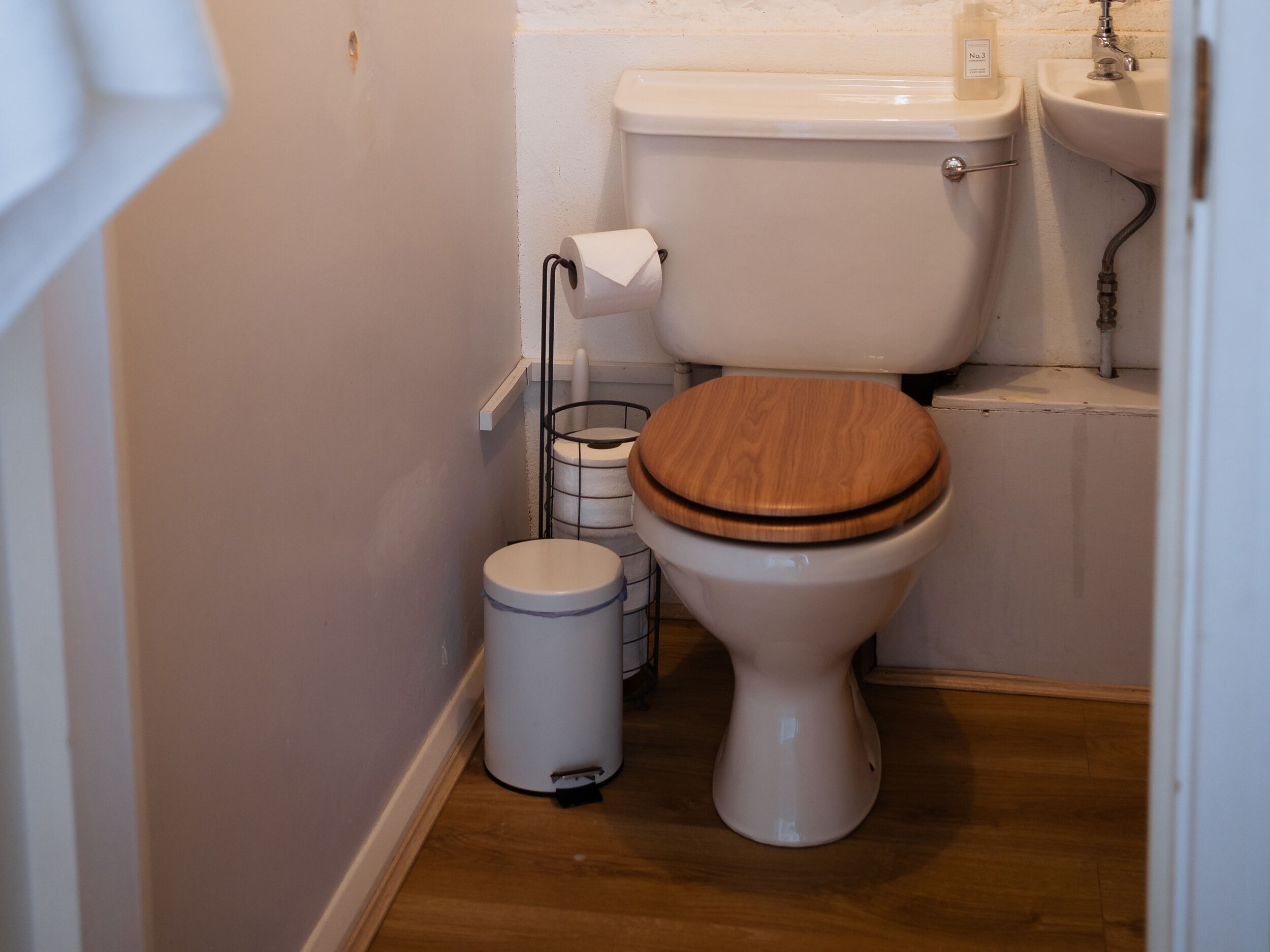 A small bathroom with a toilet, a sink, and a trash can.