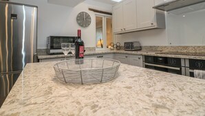 Une cuisine moderne avec un réfrigérateur en acier inoxydable, une bouteille de vin et un panier en fil métallique posé sur le comptoir.