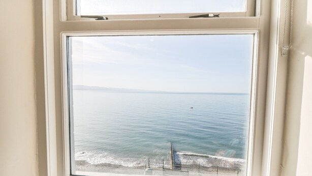 A window with a view of the sea and a distant shoreline. - 11 Marine Terrace (Criccieth)