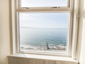 A window with a view of the sea and a distant shoreline. - 11 Marine Terrace (Criccieth)