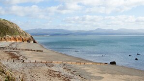 A coastal beach with a wooden walkway and rocky terrain. - 11 Marine Terrace (Criccieth)