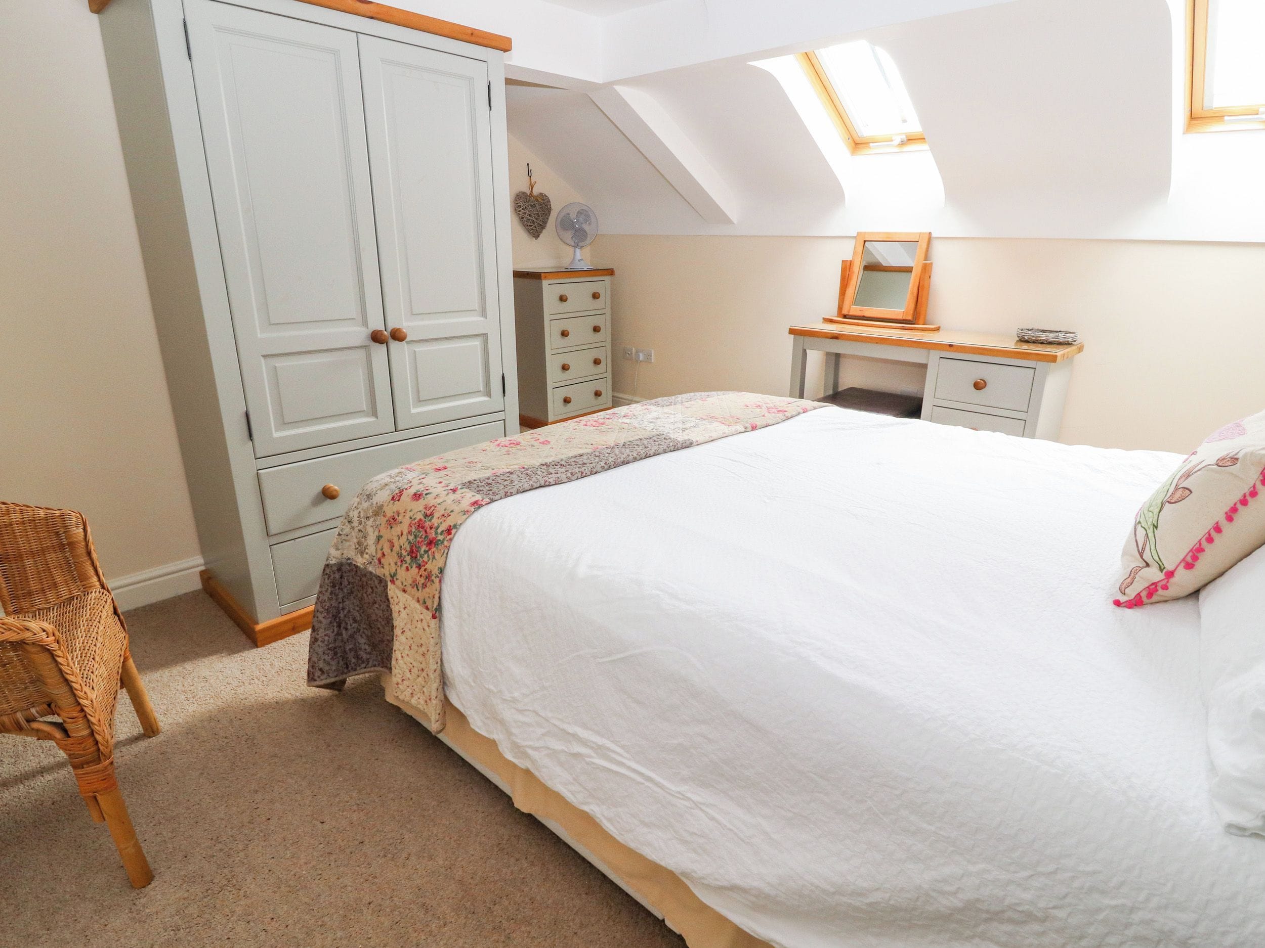 A bedroom with a large bed, a wardrobe, a desk, and a chair.