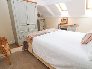 A bedroom with a large bed, a wardrobe, a desk, and a chair. - The Shippon (Tarporley)