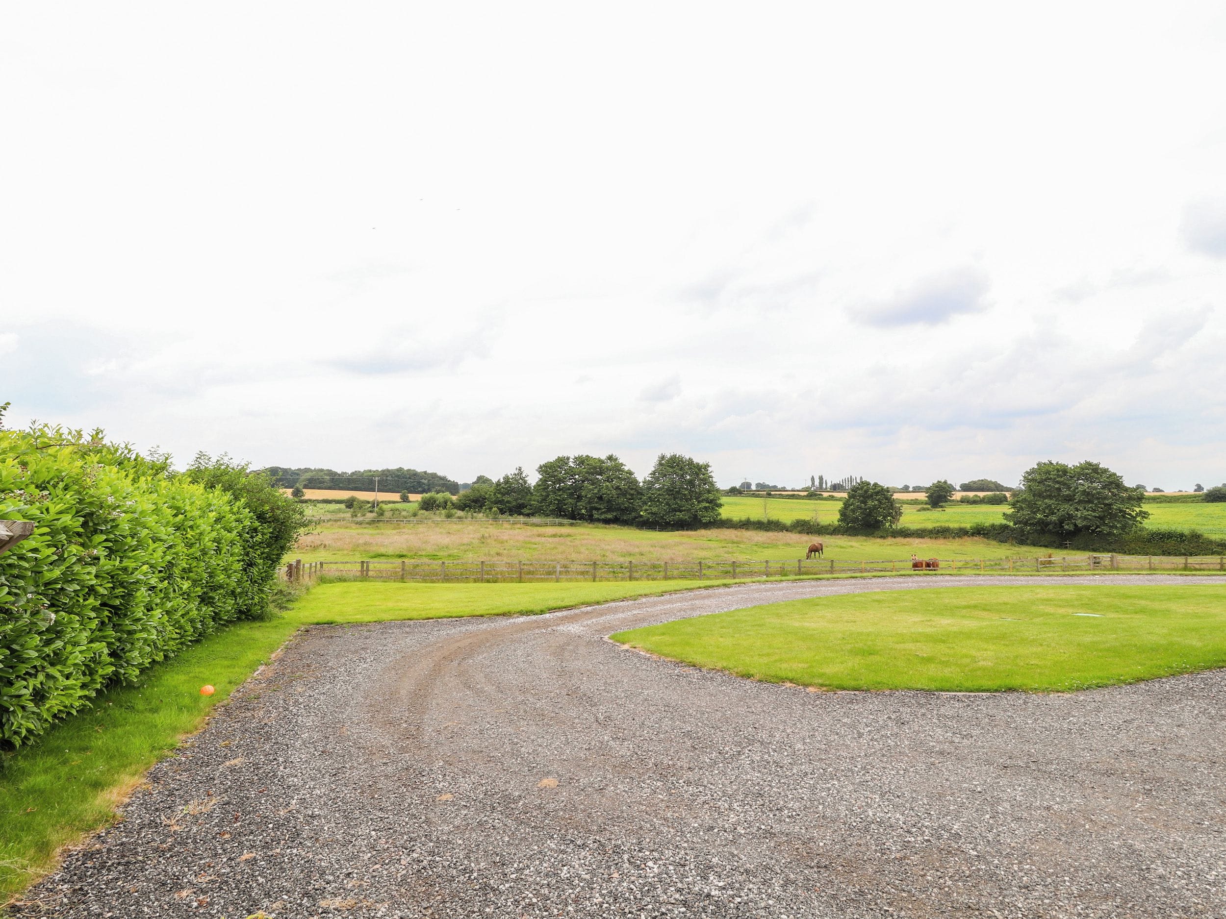A gravel path curving through a rural landscape with green fields and trees.