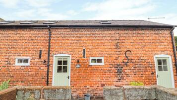 A brick building with two green doors, a small window, and a sign that reads "The Shoppan."