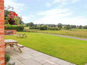 A patio with a picnic table and a hanging flower basket. - The Shippon (Tarporley)