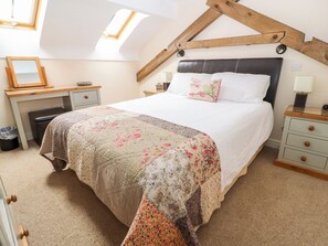 A bedroom with a large bed, a desk, and a chair. There is a skylight above the bed. - The Shippon (Tarporley)