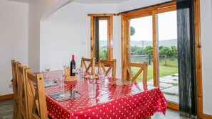 A dining area with a red polka dot tablecloth, wooden chairs, and a bottle of wine. - Ptarmigan (Grantown-on-Spey)