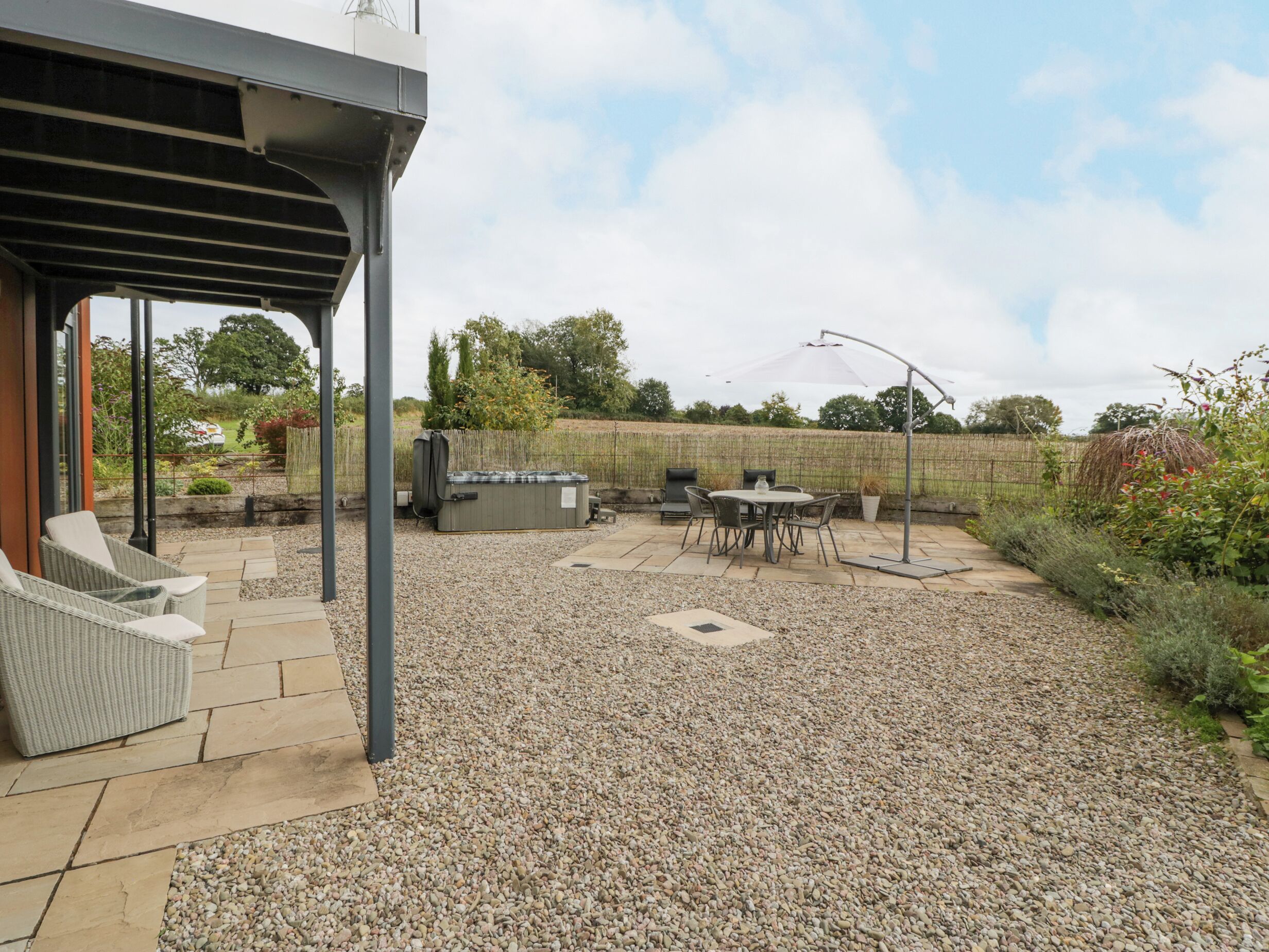 Un patio couvert avec des sièges d’extérieur, un jacuzzi et une structure en forme de pergola.