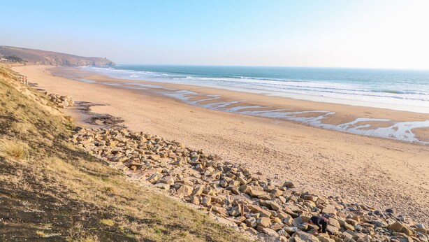 Ein Küstenstrand mit felsigem Gelände und freiem Blick auf den Ozean.