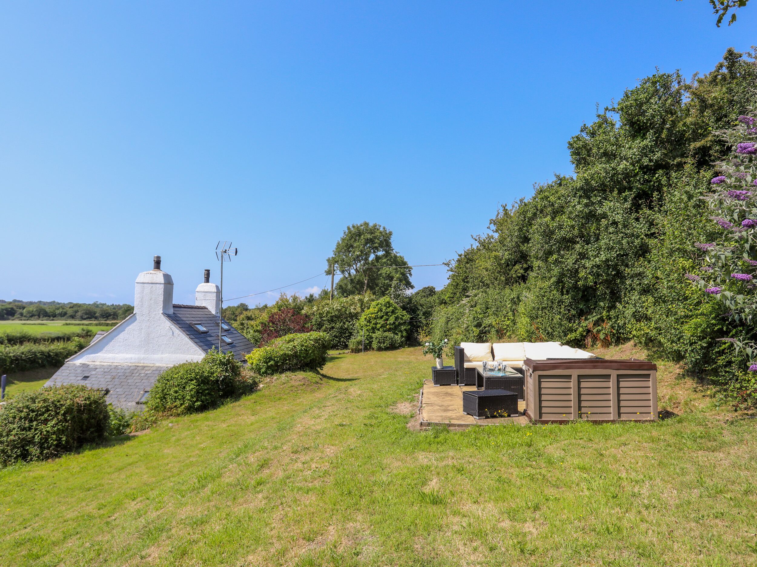A house with a sloped roof, a chimney, and a small shed with outdoor seating.