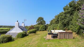 A house with a sloped roof, a chimney, and a small shed with outdoor seating.