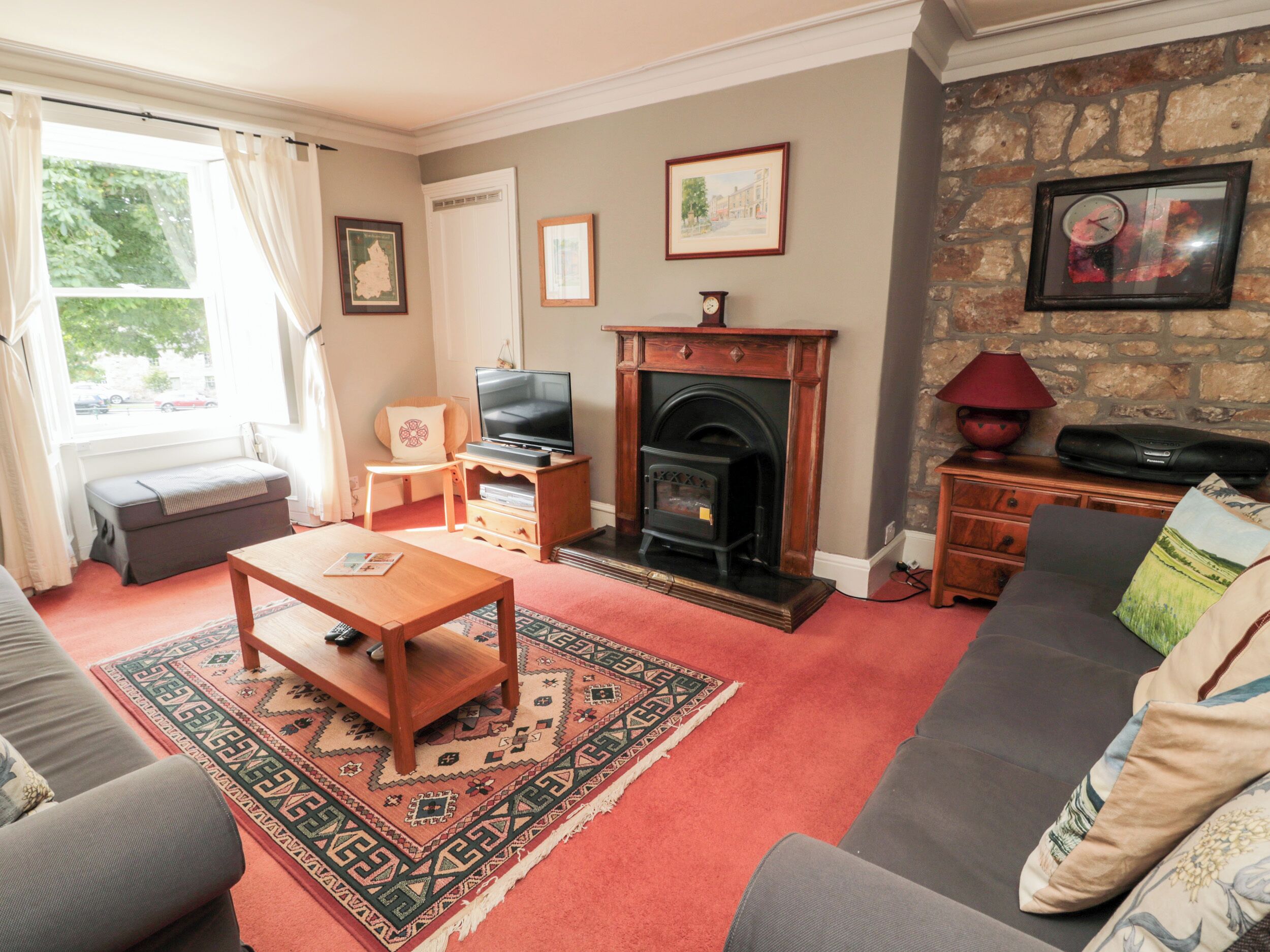 A living room with a fireplace, sofa, television, and a rug.