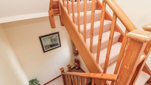 Una escalera de madera con escalones alfombrados en tono beige y barandilla de madera.