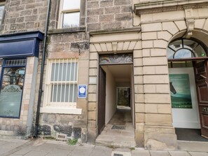 A stone building with a narrow entrance, a sign for self-catering, and a poster with a horse. - Simonside Apartment (Morpeth)