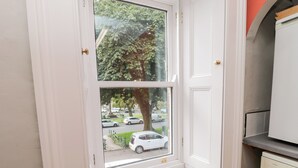 Una ventana con vistas a una calle y coches estacionados.