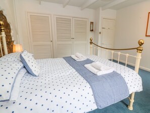 A bedroom with a bed, white double doors, and a blue carpet. - Coth Skyber (Hayle)