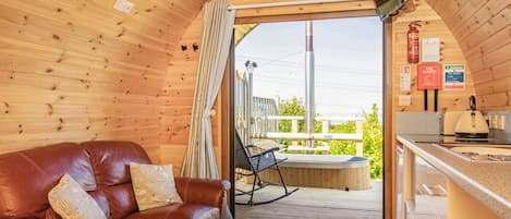 A cozy cabin interior with a leather sofa, a dining area, and a view of the outdoors.