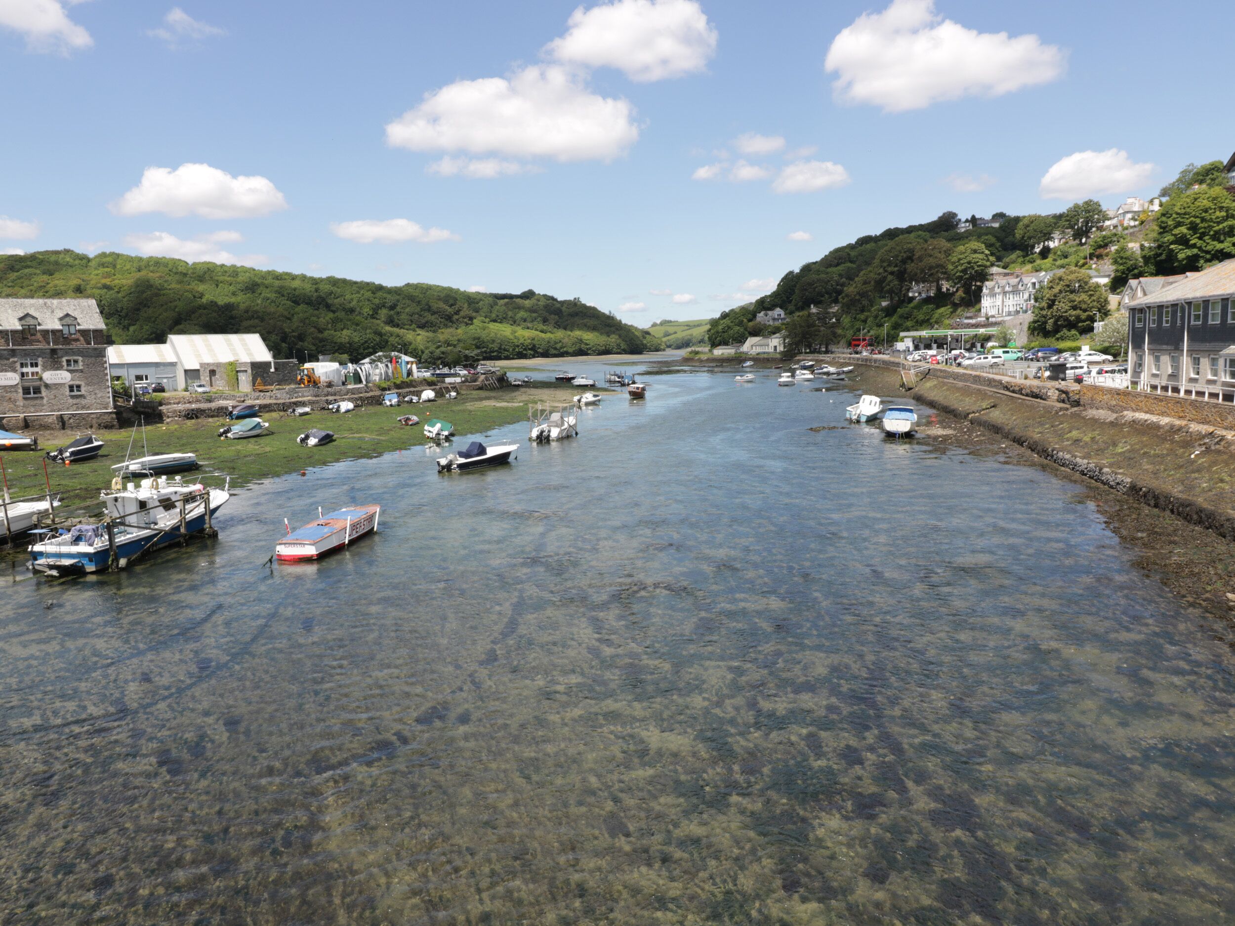 A river with boats docked along the banks, surrounded by buildings and greenery.