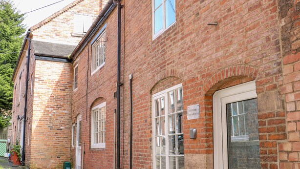A red brick building with white-framed windows and a door, labeled "End Cottage Town Hall Yard." - End Cottage (Ashbourne)
