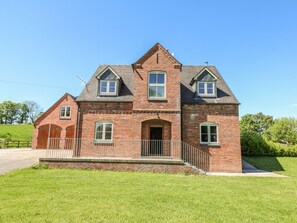 A two-story brick house with a central entrance, a small porch, and a fenced yard.
