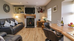 Ein modernes Wohnzimmer mit Kamin, Ledersofa, Holzesstisch und Wand-Fernseher.