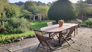 A wooden table with chairs in a garden area with a pergola and potted plants. - Church View (Salisbury)