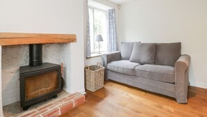 A cozy living room with a fireplace, a grey sofa, and a window with curtains. - Church View (Salisbury)