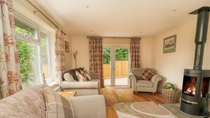 A cozy living room with a sofa, armchairs, a fireplace, and a view of the outdoors. - New Peny (Llandrindod Wells)
