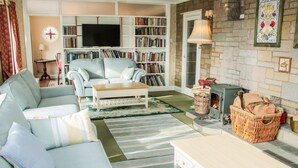 Una sala de estar acogedora con un sofá, una mesa de centro, una chimenea y una estantería llena de libros.