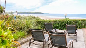 Une terrasse avec quatre chaises et une table donnant sur une plage.