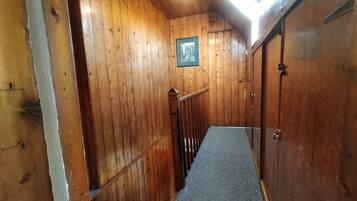 A wooden interior with a carpeted staircase, wooden walls, and a framed picture on the wall.