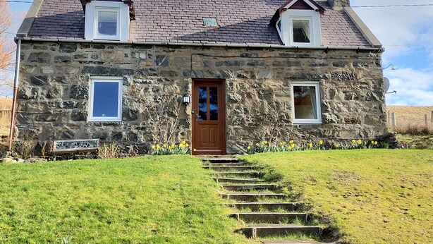 A stone house with a wooden door, two windows, and a chimney. - Ornum (Thurso)