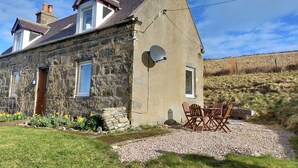 A stone house with a sloped roof, a satellite dish, and a gravel driveway. - Ornum (Thurso)
