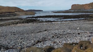 A rocky beach with a large cliff and a breakwater. - Ornum (Thurso)