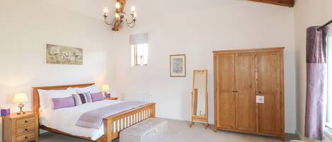 A bedroom with a wooden bed, bedside lamps, a wooden wardrobe, and a chandelier.
