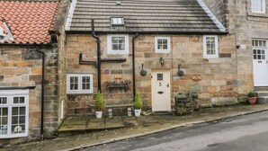 A stone building with a tiled roof, a white door, and a sign that reads "Willow Noor." - Willow Nook (Whitby)
